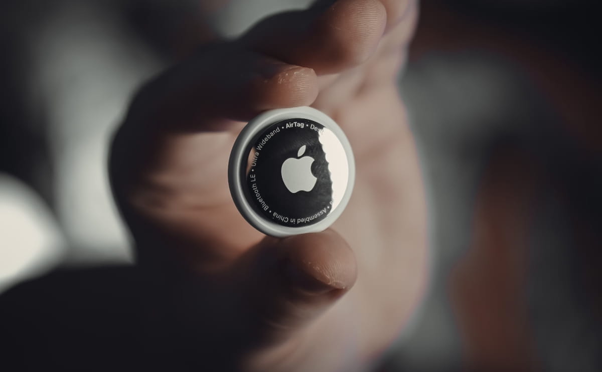Close-up of an Apple AirTag held between two fingers